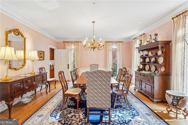 dining room with an inviting chandelier, ornamental molding, and light hardwood / wood-style flooring