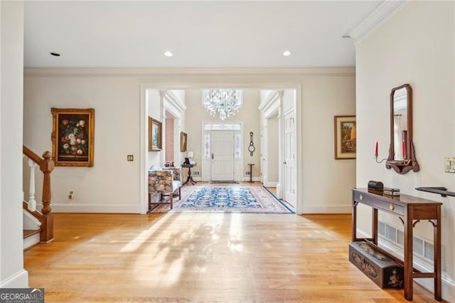 foyer featuring a chandelier, light hardwood / wood-style flooring, and ornamental molding