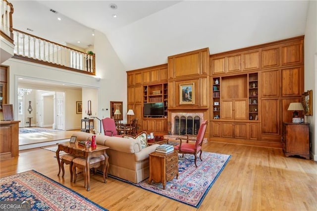 living room featuring high vaulted ceiling and light hardwood / wood-style flooring