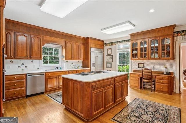 kitchen featuring light wood-type flooring, stainless steel appliances, a kitchen island, and backsplash