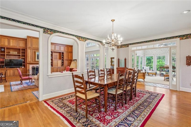 dining space featuring crown molding, an inviting chandelier, and hardwood / wood-style flooring