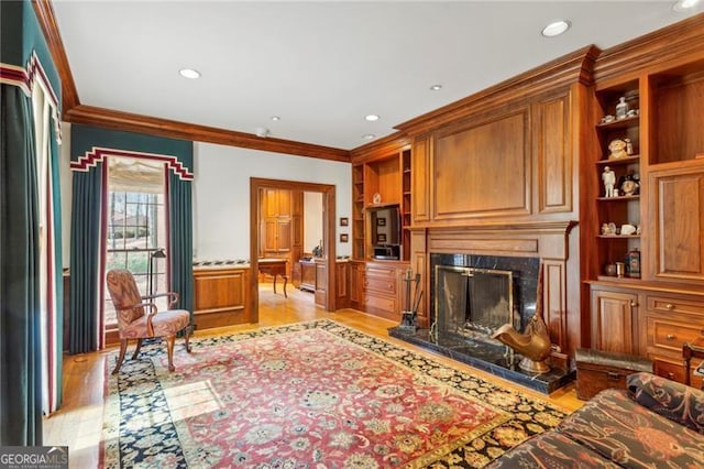 living room featuring built in shelves, a high end fireplace, ornamental molding, and light wood-type flooring