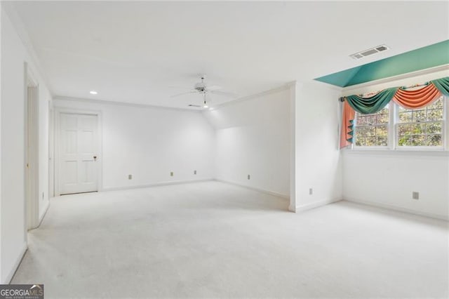 spare room featuring ceiling fan, light colored carpet, and crown molding