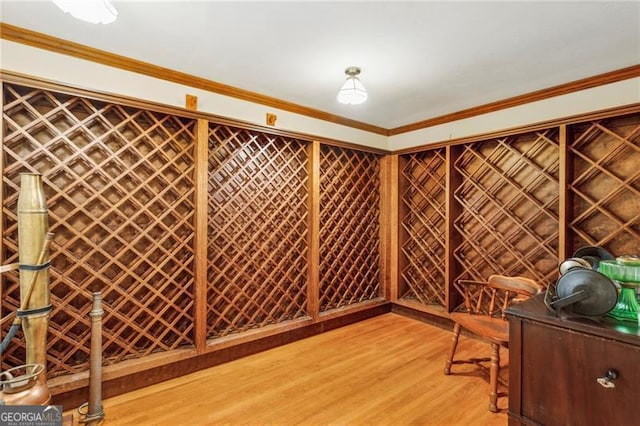 wine area featuring light wood-type flooring and crown molding