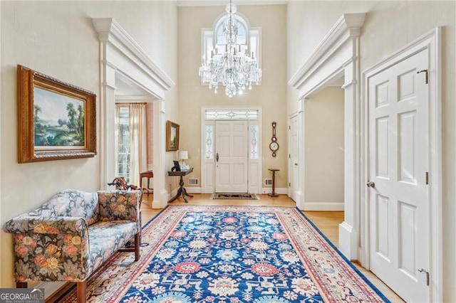 entryway featuring a towering ceiling, light hardwood / wood-style flooring, and an inviting chandelier