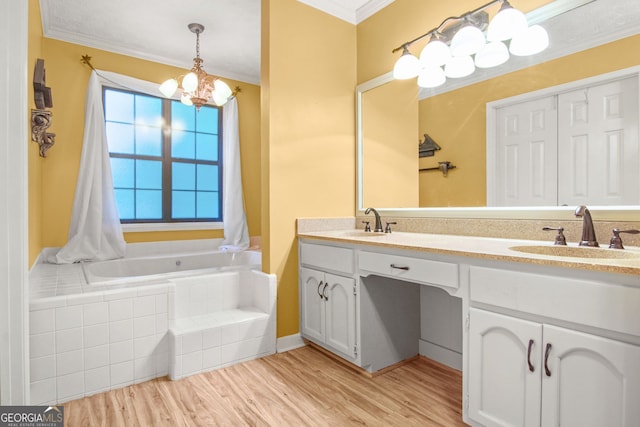 bathroom featuring an inviting chandelier, tiled bath, hardwood / wood-style floors, vanity, and ornamental molding