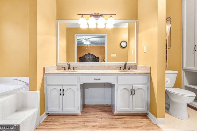 bathroom with hardwood / wood-style floors, vanity, toilet, and tiled tub