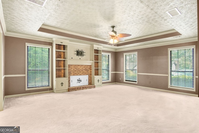 unfurnished living room with a raised ceiling, crown molding, ceiling fan, and carpet