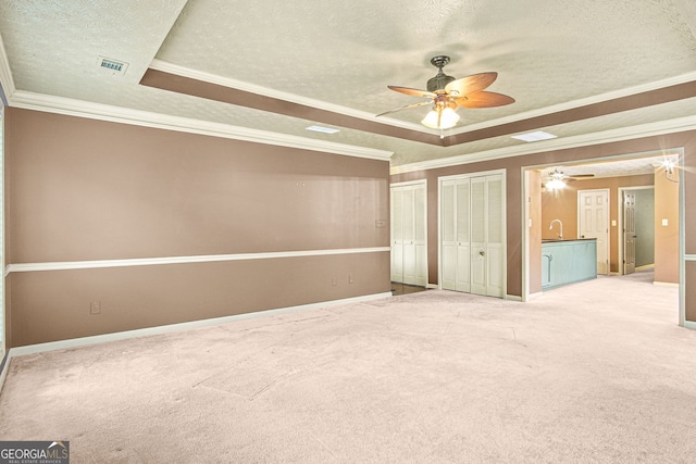 unfurnished bedroom with ceiling fan, ornamental molding, carpet floors, and a tray ceiling