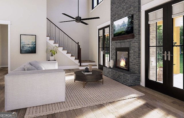 living room with ceiling fan, french doors, a high ceiling, dark hardwood / wood-style flooring, and a fireplace