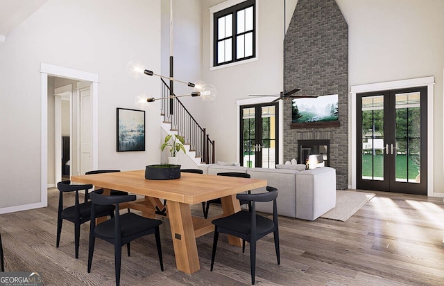 dining space featuring french doors, ceiling fan with notable chandelier, hardwood / wood-style flooring, and high vaulted ceiling