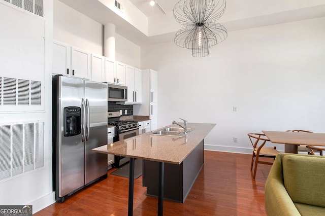 kitchen featuring sink, stainless steel appliances, light stone counters, a kitchen island with sink, and white cabinets