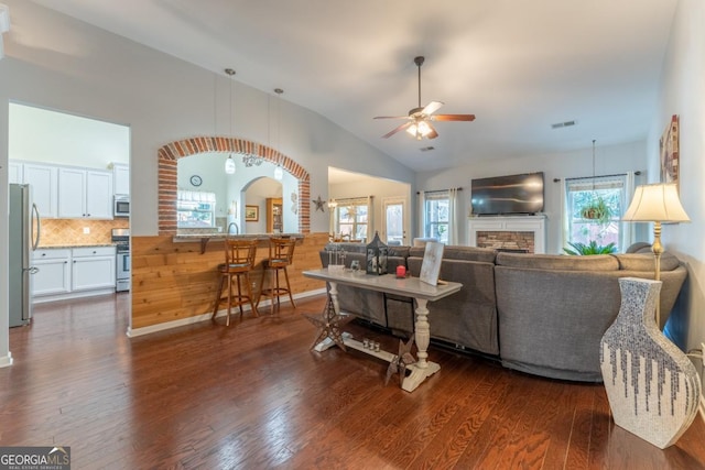 living room featuring ceiling fan, lofted ceiling, dark wood-type flooring, and a wealth of natural light