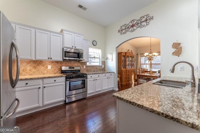 kitchen featuring appliances with stainless steel finishes, dark hardwood / wood-style flooring, light stone counters, sink, and white cabinets