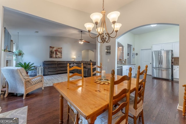 dining area featuring ceiling fan with notable chandelier, dark wood-type flooring, and lofted ceiling