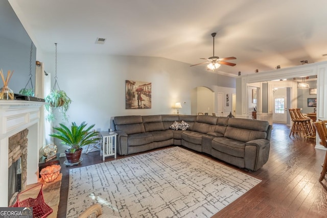 living room with a stone fireplace, ceiling fan, dark wood-type flooring, and lofted ceiling