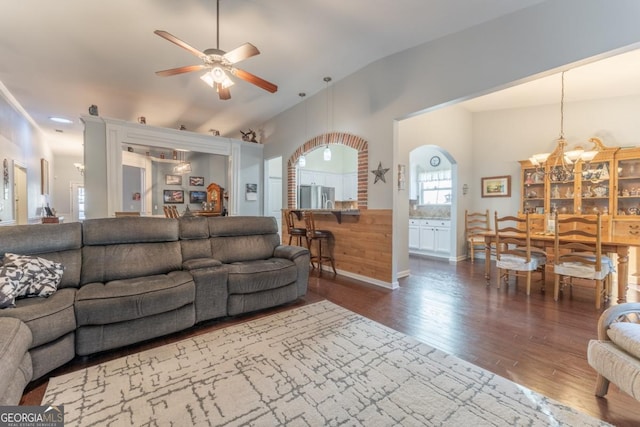 living room with ceiling fan with notable chandelier, dark hardwood / wood-style flooring, and lofted ceiling