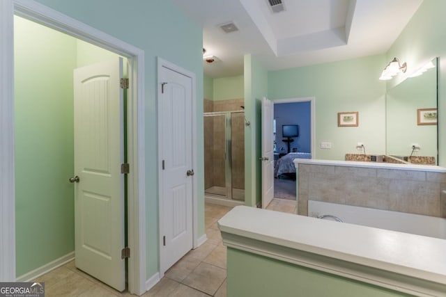 bathroom with a tray ceiling, tile patterned flooring, and walk in shower