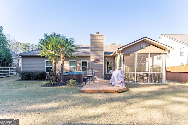 rear view of property with a sunroom, a hot tub, a lawn, and a wooden deck