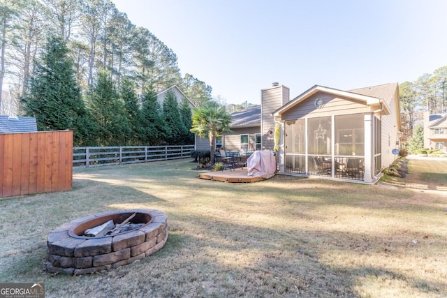 view of yard featuring a sunroom, a fire pit, and a wooden deck