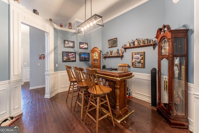 bar with white cabinets, ornamental molding, hanging light fixtures, and dark wood-type flooring