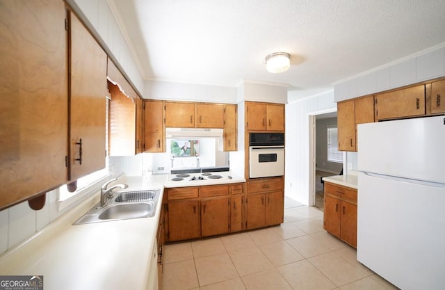 kitchen with sink, white appliances, crown molding, and light tile patterned floors