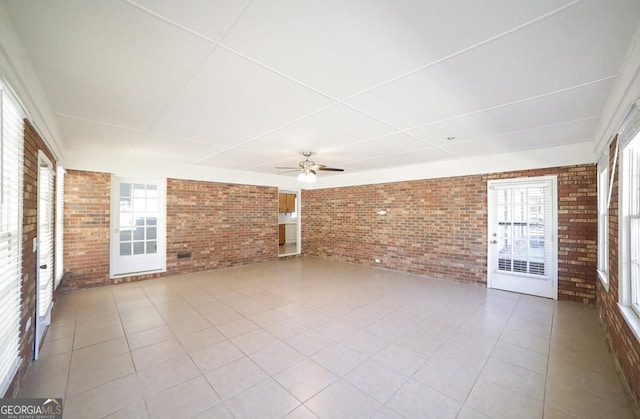 interior space featuring ceiling fan, a wealth of natural light, and brick wall