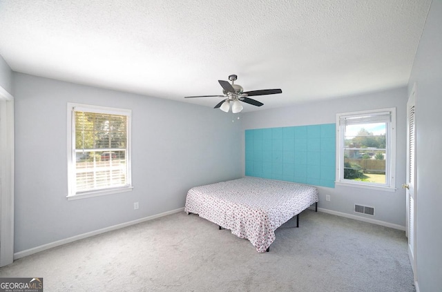 carpeted bedroom featuring a textured ceiling and ceiling fan