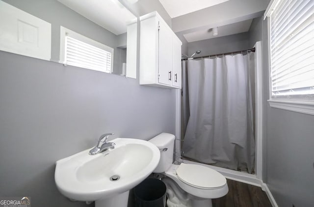 bathroom featuring hardwood / wood-style floors, toilet, curtained shower, and sink