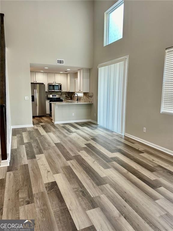 unfurnished living room featuring a towering ceiling and light hardwood / wood-style floors