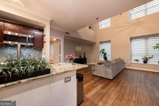 kitchen featuring decorative backsplash, ornamental molding, a healthy amount of sunlight, and hardwood / wood-style floors