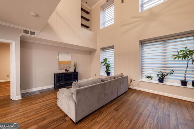 living room featuring a high ceiling, dark wood-type flooring, and crown molding