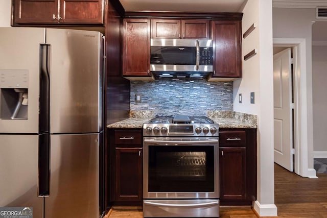 kitchen with hardwood / wood-style floors, ornamental molding, tasteful backsplash, light stone counters, and stainless steel appliances