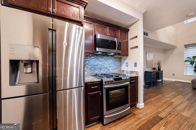 kitchen featuring stainless steel appliances, light stone counters, light hardwood / wood-style flooring, backsplash, and dark brown cabinets