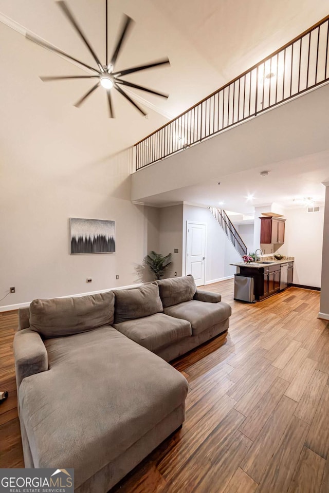 living room with sink, a high ceiling, and light wood-type flooring