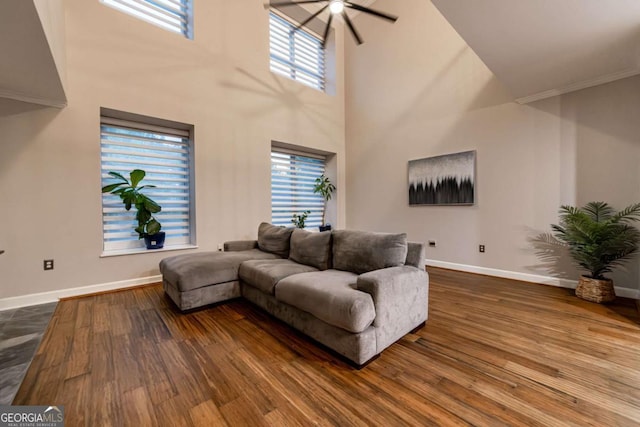 living room featuring hardwood / wood-style floors, ceiling fan, and a high ceiling