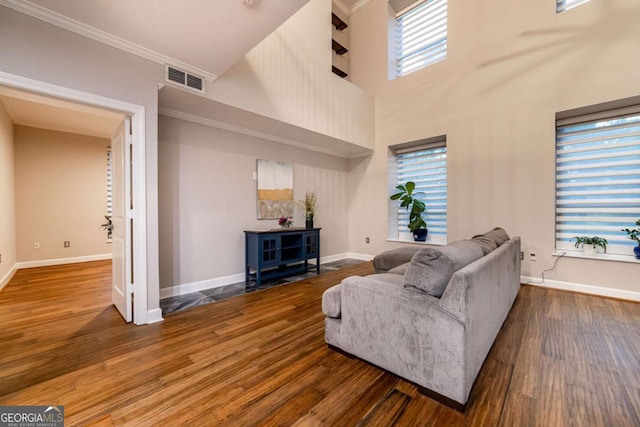 living room with plenty of natural light, a high ceiling, dark hardwood / wood-style floors, and ornamental molding