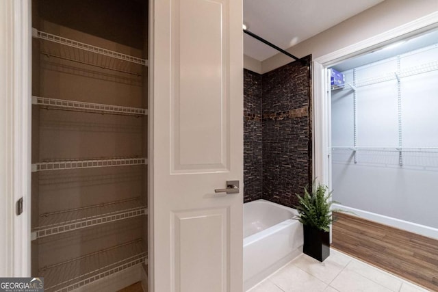 bathroom with hardwood / wood-style floors and tiled shower / bath combo