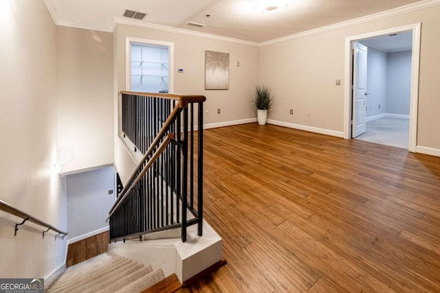 stairway with hardwood / wood-style flooring and crown molding