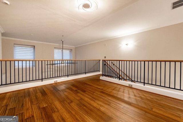 empty room featuring wood-type flooring and ornamental molding