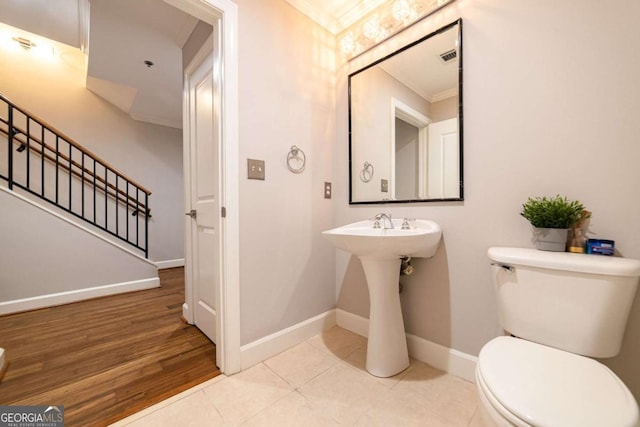 bathroom with wood-type flooring, toilet, and crown molding