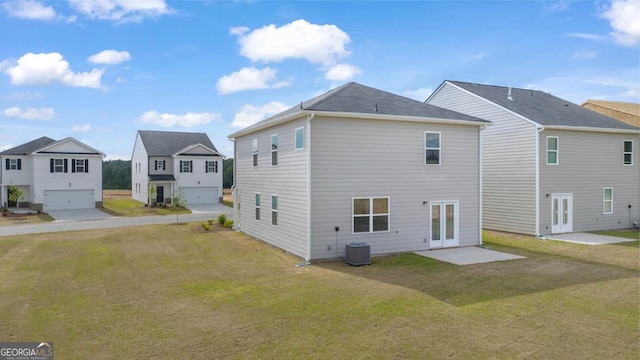 rear view of house featuring a lawn, a garage, and french doors