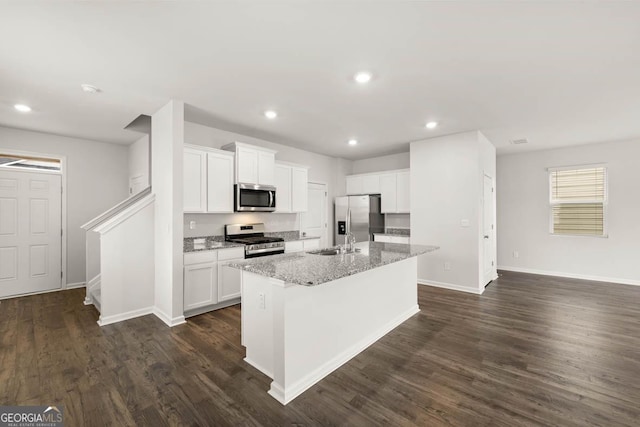 kitchen with light stone counters, white cabinetry, an island with sink, and appliances with stainless steel finishes