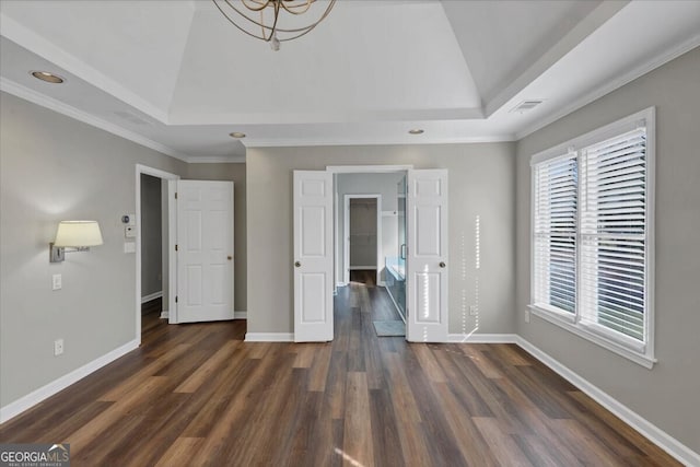 unfurnished bedroom featuring a raised ceiling, ornamental molding, dark wood-type flooring, and a chandelier