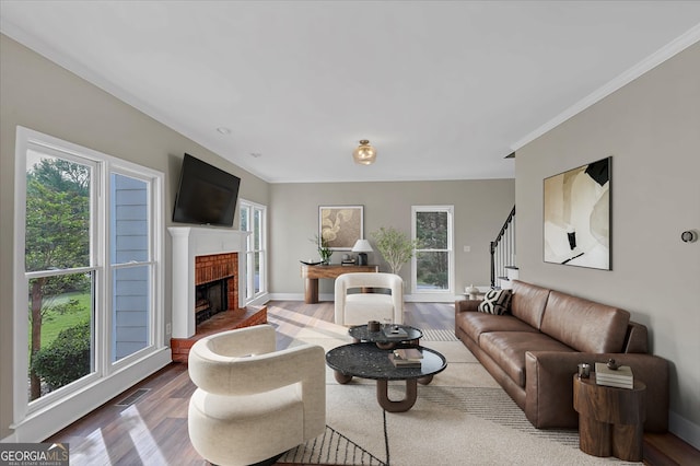 living room featuring hardwood / wood-style flooring, a brick fireplace, and crown molding