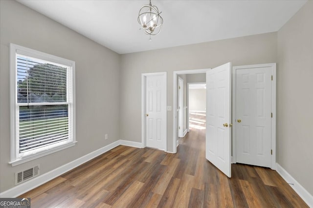 unfurnished bedroom featuring dark hardwood / wood-style flooring and a notable chandelier