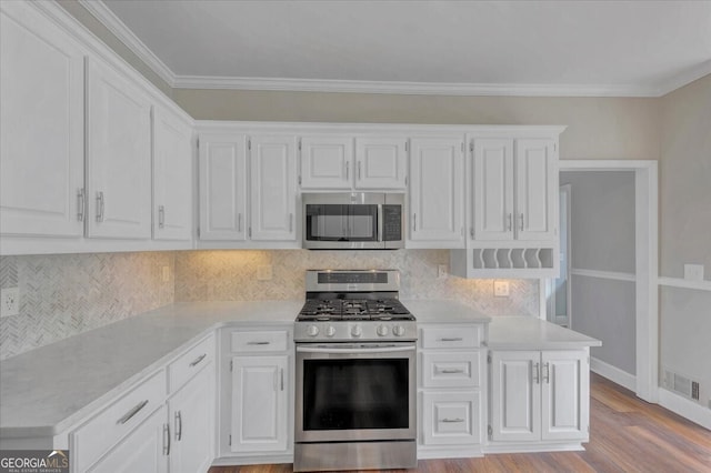 kitchen featuring light hardwood / wood-style flooring, crown molding, decorative backsplash, white cabinets, and appliances with stainless steel finishes