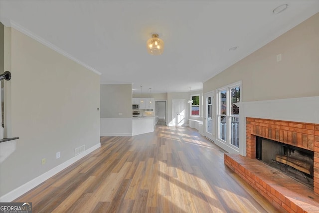 unfurnished living room with a fireplace, hardwood / wood-style flooring, and crown molding