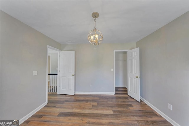 empty room featuring dark hardwood / wood-style floors and an inviting chandelier