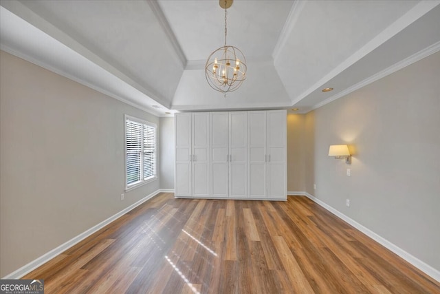 unfurnished bedroom with hardwood / wood-style flooring, ornamental molding, a tray ceiling, and a chandelier